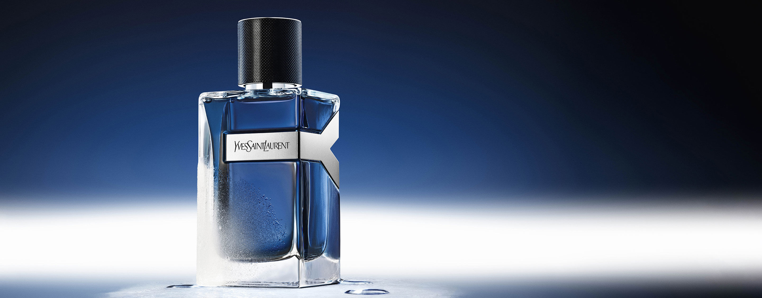 Flacone da 100 ml di YSL Y Eau de Toilette Intense Iced Cologne, ghiacciato e con gocce d'acqua, che riflette un'atmosfera blu glaciale.