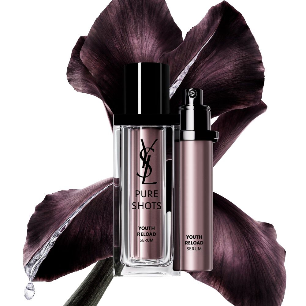 Pure Shots Youth Reload Serum di YSL Beauty e la sua ricarica sostenibile, posizionati davanti a un fiore di iris viola scuro.