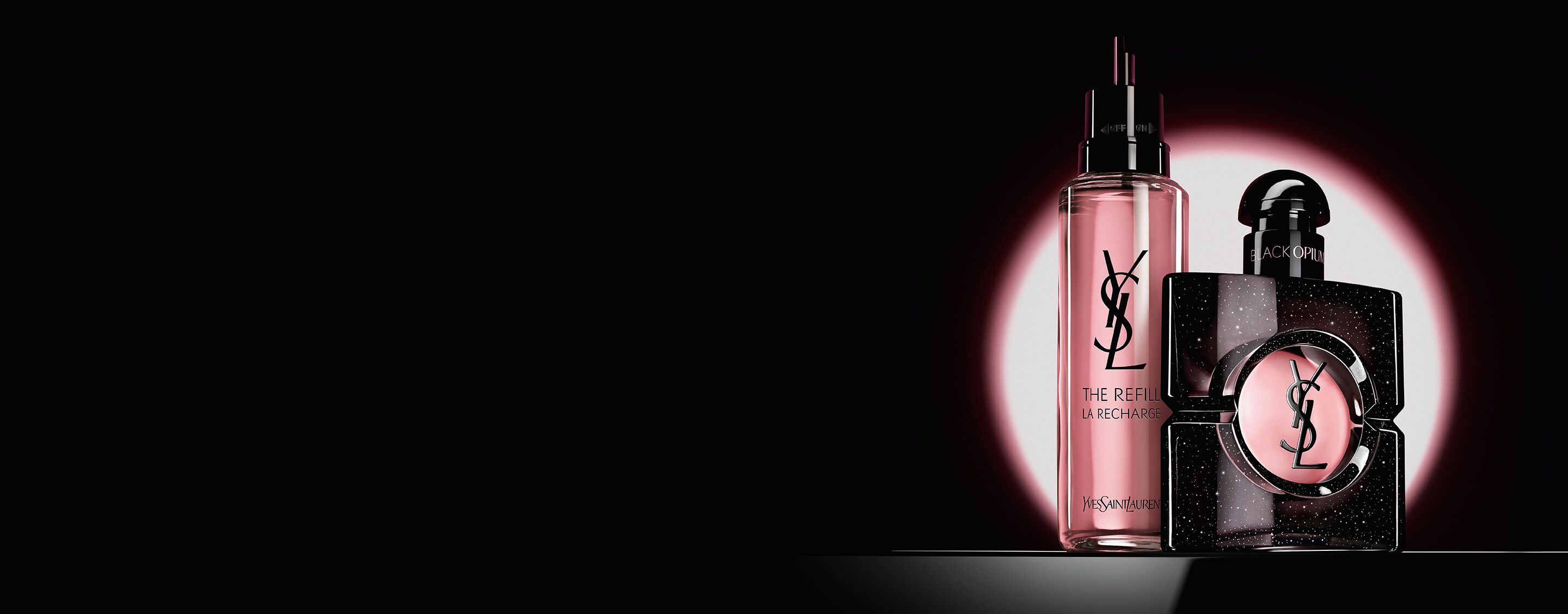 Flacone Black Opium Eau de Parfum accanto al suo flacone di ricarica in vetro da 100 ml con il logo YSL.