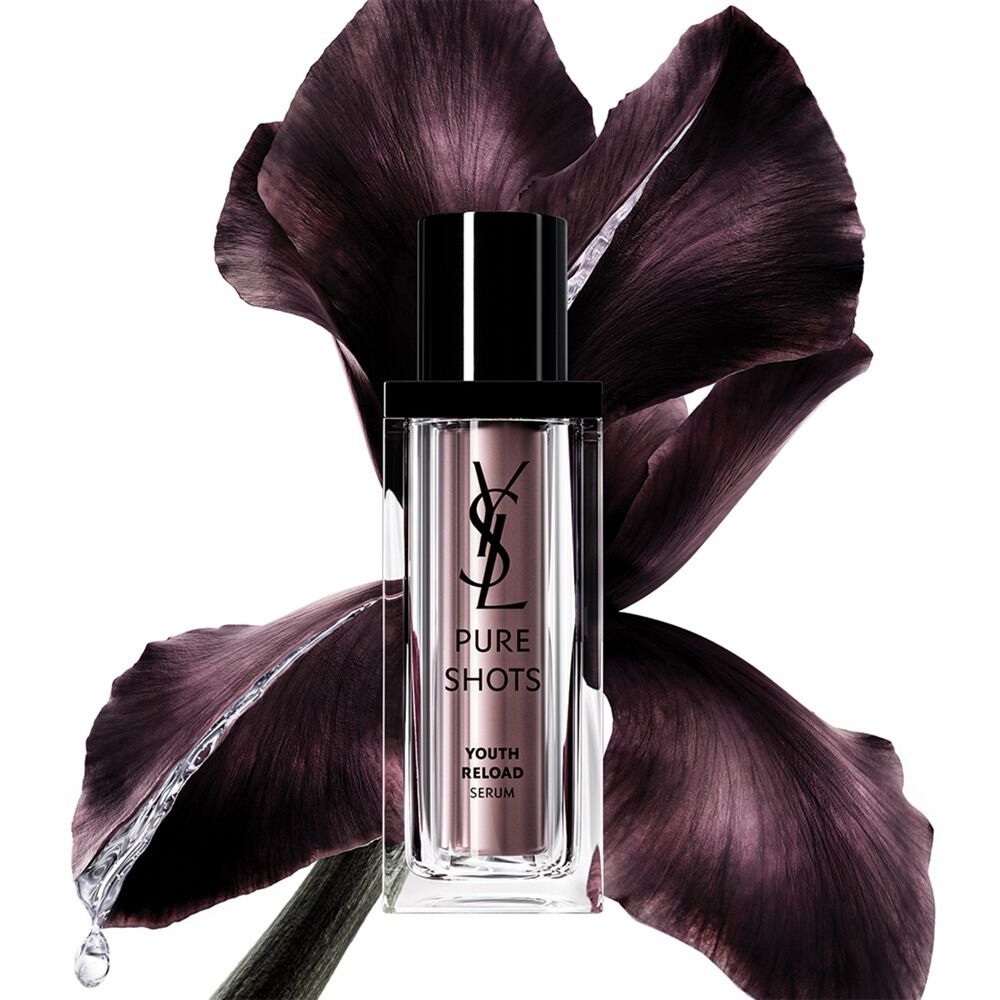 Flacone del Pure Shots Youth Reload Serum di YSL Beauty, elegantemente posizionato davanti a un fiore di iris viola scuro.