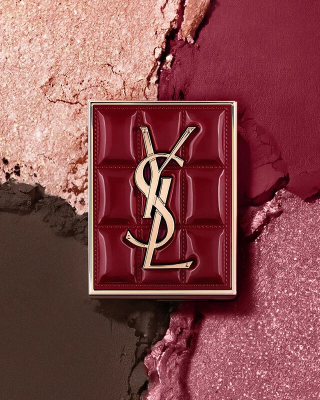 La palette YSL Couture Mini Clutch su uno sfondo di ombretti scintillanti in polvere #1982 Burgundy Millesime.
