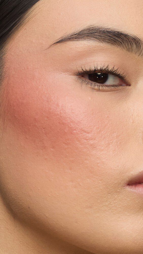 Primo piano del viso di una modella con il look Make Me Blush: Cipria n. 37 Peachy Nude stratificata con la Crema n. 90 Toffee Temptation per un incarnato baciato dal sole.