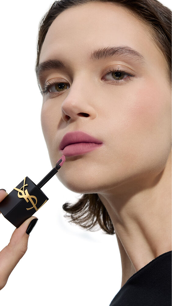 Modella con tono di pelle chiaro, applica una tonalità malva-soft fredda di YSL THE INKS BLUR con l'applicatore a bacchetta.
