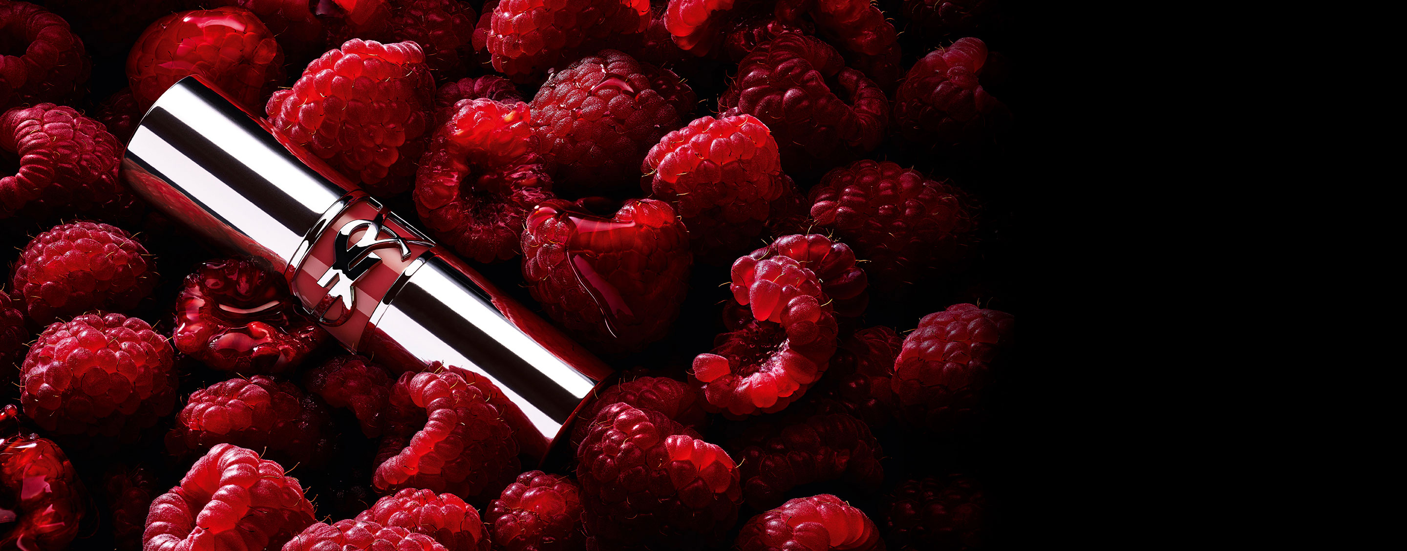 Rossetto YSL LOVESHINE Berry Crush, tubetto argento con logo YSL color bacca, adagiato tra lamponi freschi.