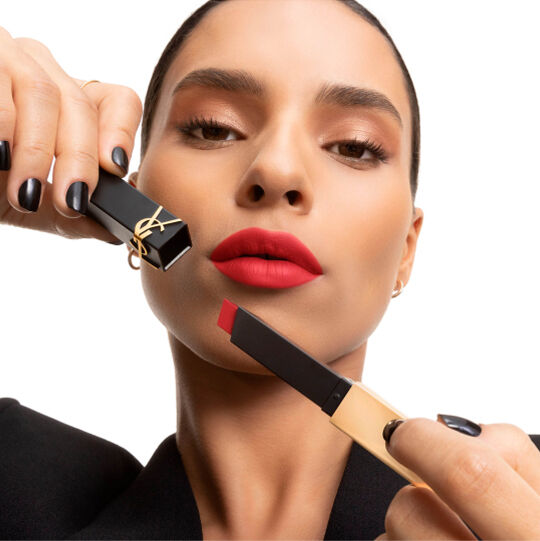 Mano che mostra un rossetto YSL quadrato rosa tenue accanto alla guancia.