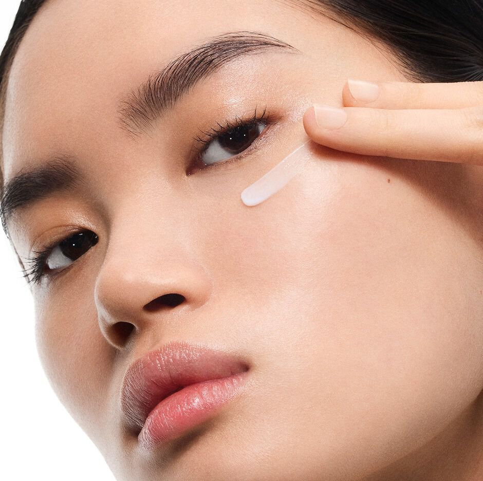 La modella dalla pelle chiara Mingma applica la crema Eye Reboot Pure Shots di YSL sotto l'occhio, mostrandone la texture delicata.