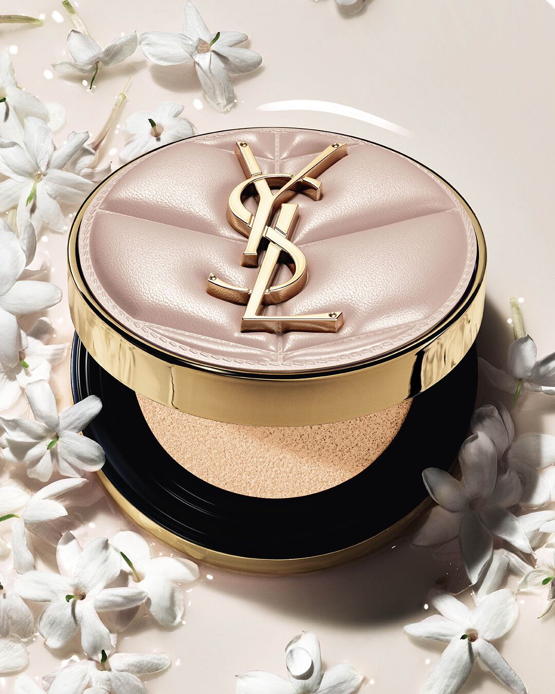 Primo piano di YSL SKIN AFFAIR SOFT GLOW CUSHION immerso in una pozza di fondotinta liquido e fiori di gelsomino. Finish radioso e sensoriale.