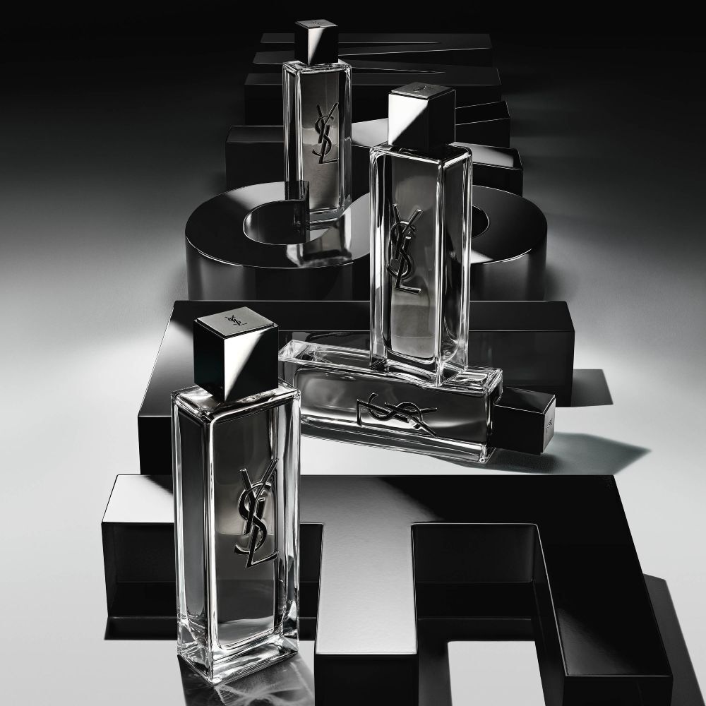 Vista dall’alto di più flaconi di MYSLF Eau de Toilette Intense disposti su grandi lettere 3D nere che compongono la scritta MYSLF, adagiate a terra.