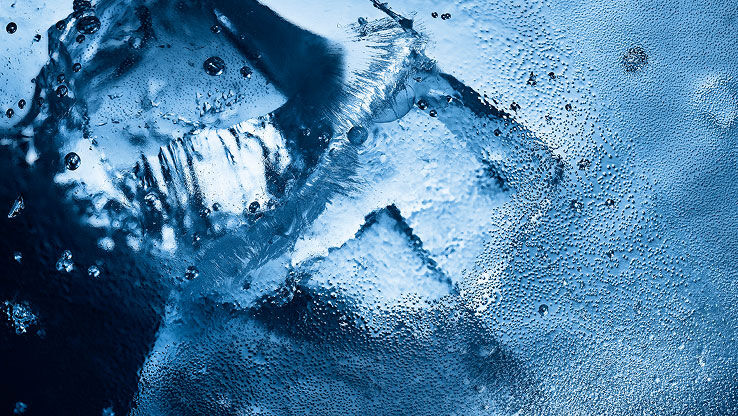 Primo piano di ghiaccio e gocce d'acqua, che evocano l'intensa freschezza glaciale di YSL Y Eau de Toilette Intense Iced Cologne.