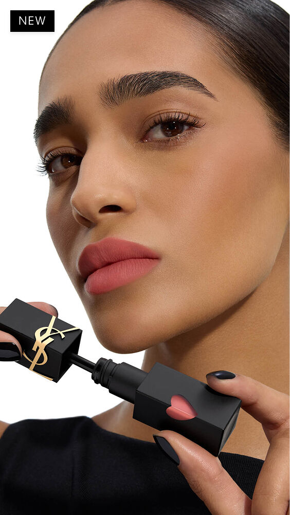 Modella con tono di pelle medio-scuro, labbra opache e sfocate in soft-focus, tiene l'applicatore di YSL THE INKS BLUR accanto al mento.