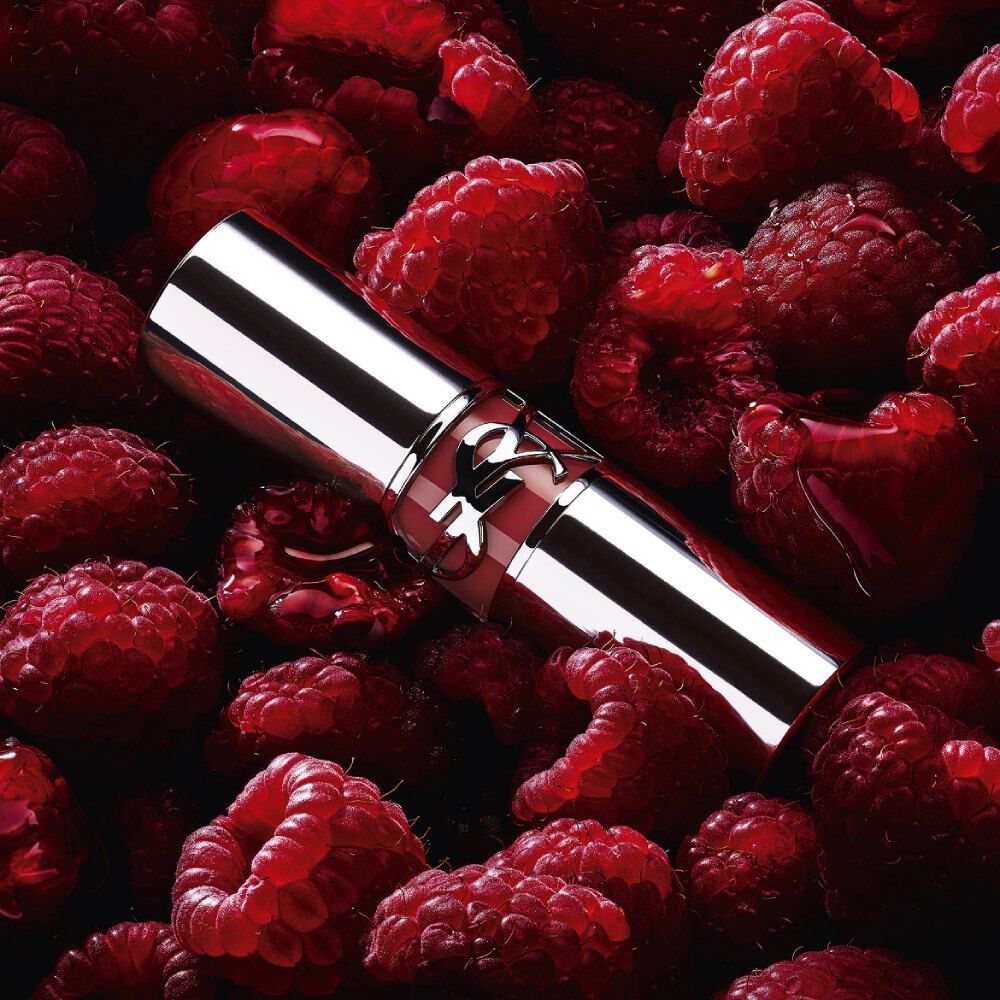 Rossetto YSL LOVESHINE Berry Crush, tubetto argento con logo YSL color berry, immerso tra lamponi freschi.
