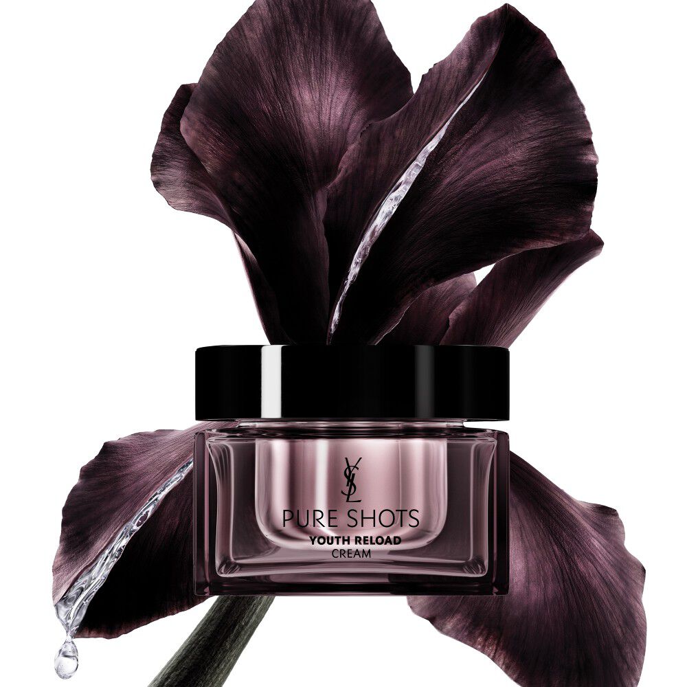 Vaso della crema Pure Shots Youth Reload di YSL Beauty, elegantemente posizionato davanti a un fiore di iris viola scuro.