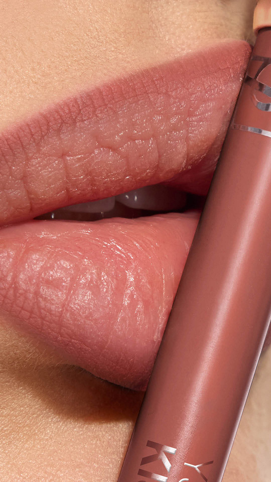 Primo piano verticale di labbra con rossetto opaco malva e relativa matita YSL.