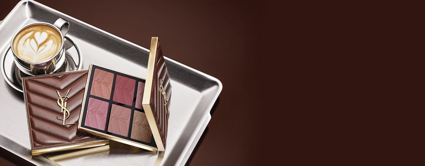 Collezione make-up YSL Fall Drop Latte con Loveshine Lip Oil, Face Palette e Make Me Blush e una tazza di caffè su un vassoio argentato