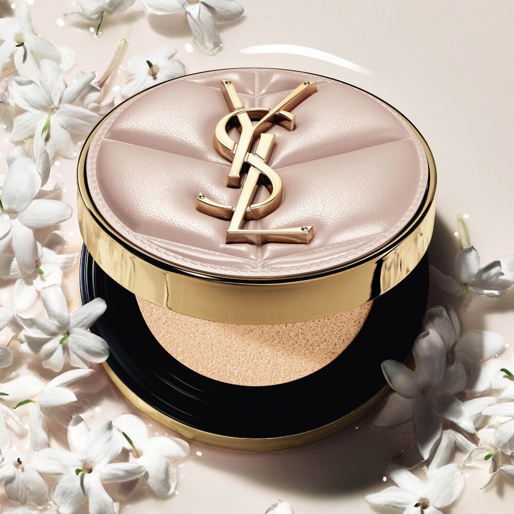 Primo piano di YSL SKIN AFFAIR SOFT GLOW CUSHION immerso in una pozza di fondotinta liquido e fiori di gelsomino. Finish radioso e sensoriale.