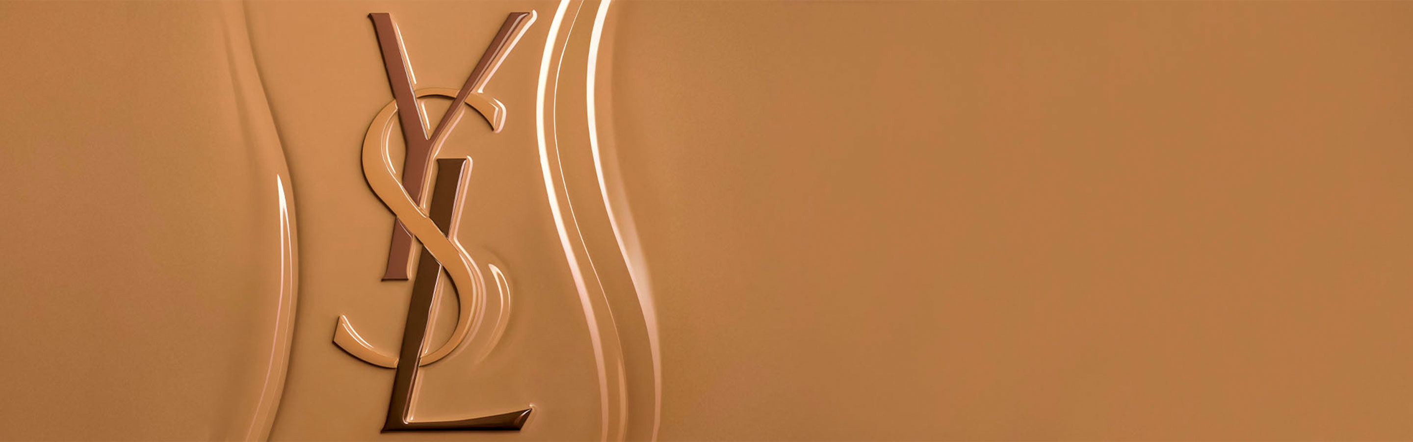Logo Yves Saint Laurent (YSL) in rilievo su una superficie testurizzata di fondotinta liquido, che mette in risalto la consistenza ricca e facilmente sfumabile del prodotto.